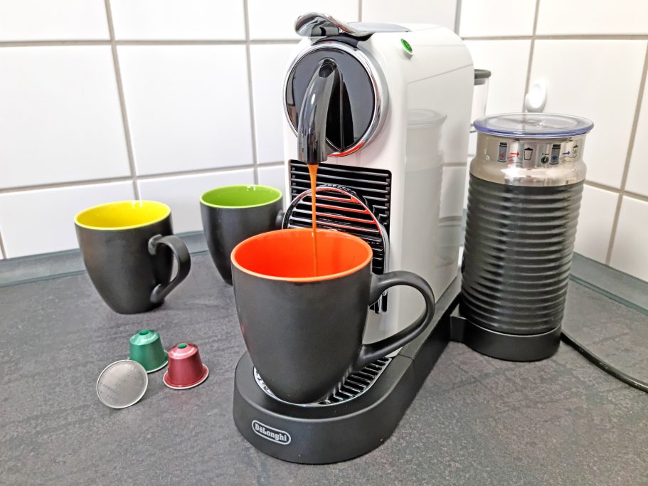 Küche Kaffeekapselmaschine mit drei Tassen und Zubehör auf einer Arbeitsfläche.