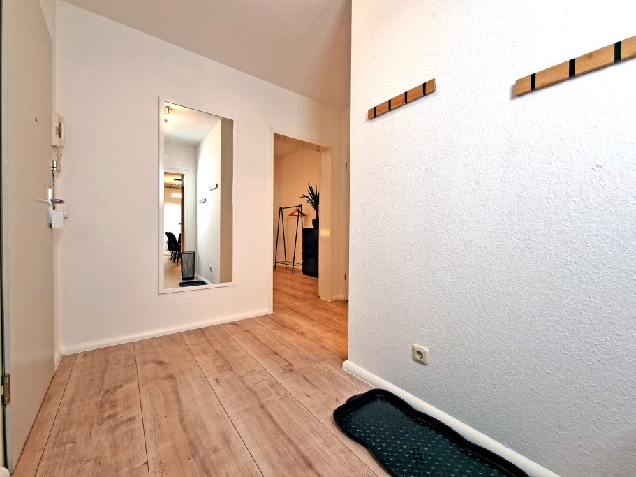 Eingangsbereich/Flur Heller Flur mit Holzfußboden, Spiegel und Garderobe an der Wand.