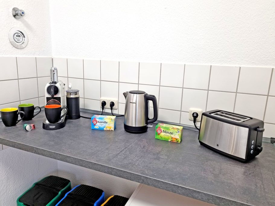 Küche Küchenzeile mit Kaffeemaschine, Wasserkocher, Toaster und Geschirr.