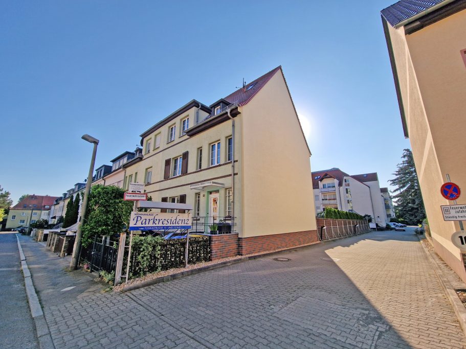 Grundstück Helle Wohnstraße mit einem gelben Gebäude und klar blauem Himmel im Hintergrund.