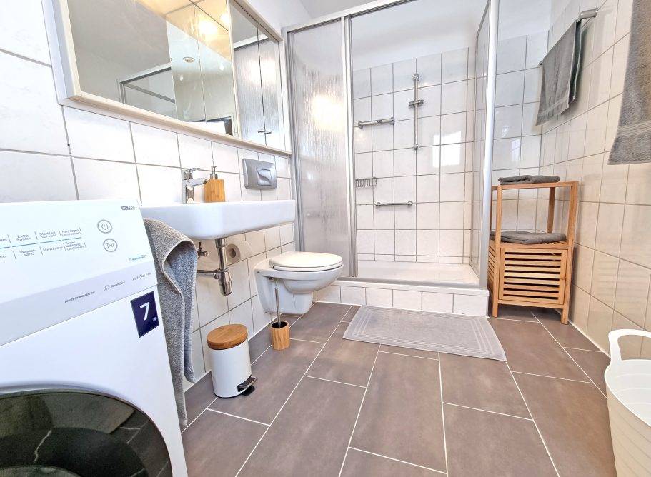 Großes Bad/Dusche Modernes Badezimmer mit Dusche, Waschmaschine, WC und Holzmöbel.