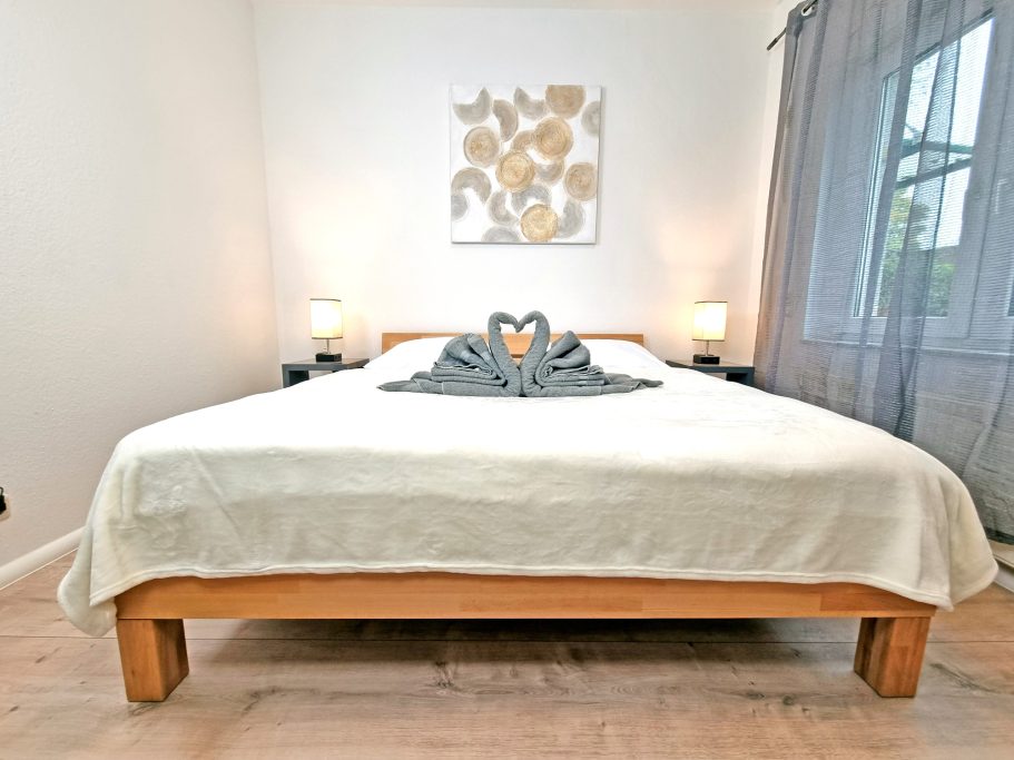 Schlafzimmer Groß Helles Schlafzimmer mit einem Bett, dekoriert mit Handtuch-Tafel und Kunstwerk an der Wand.