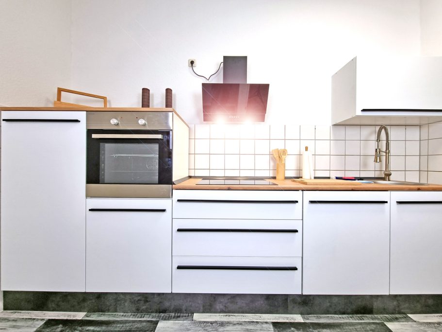 Küche Moderne Küche mit weißen Schränken, Backofen und hellem Beleuchtungselement.