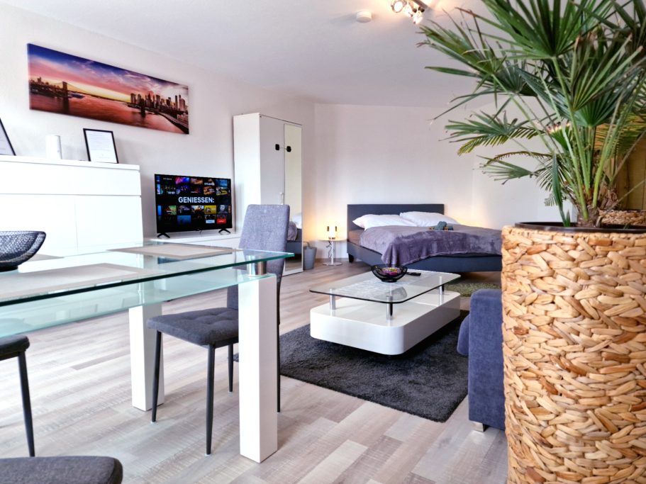 Wohnzimmer Heller Wohnraum mit eleganter Einrichtung, Esstisch und Pflanzen im Vordergrund.