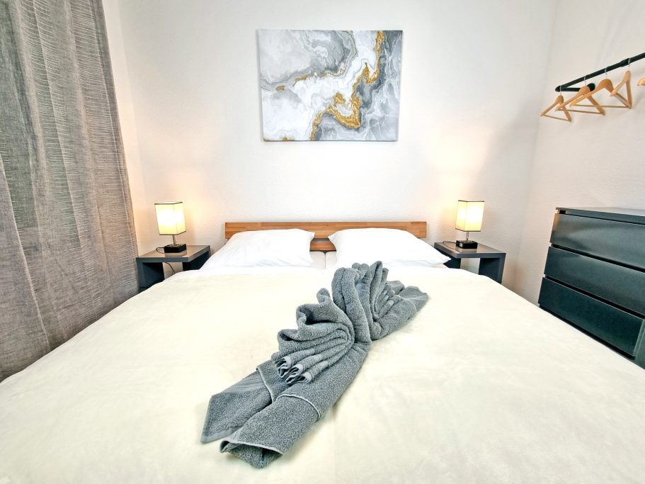 Schlafzimmer klein Gemütliches Schlafzimmer mit Doppelbett, dekorativen Kissen und modernen Lampen.