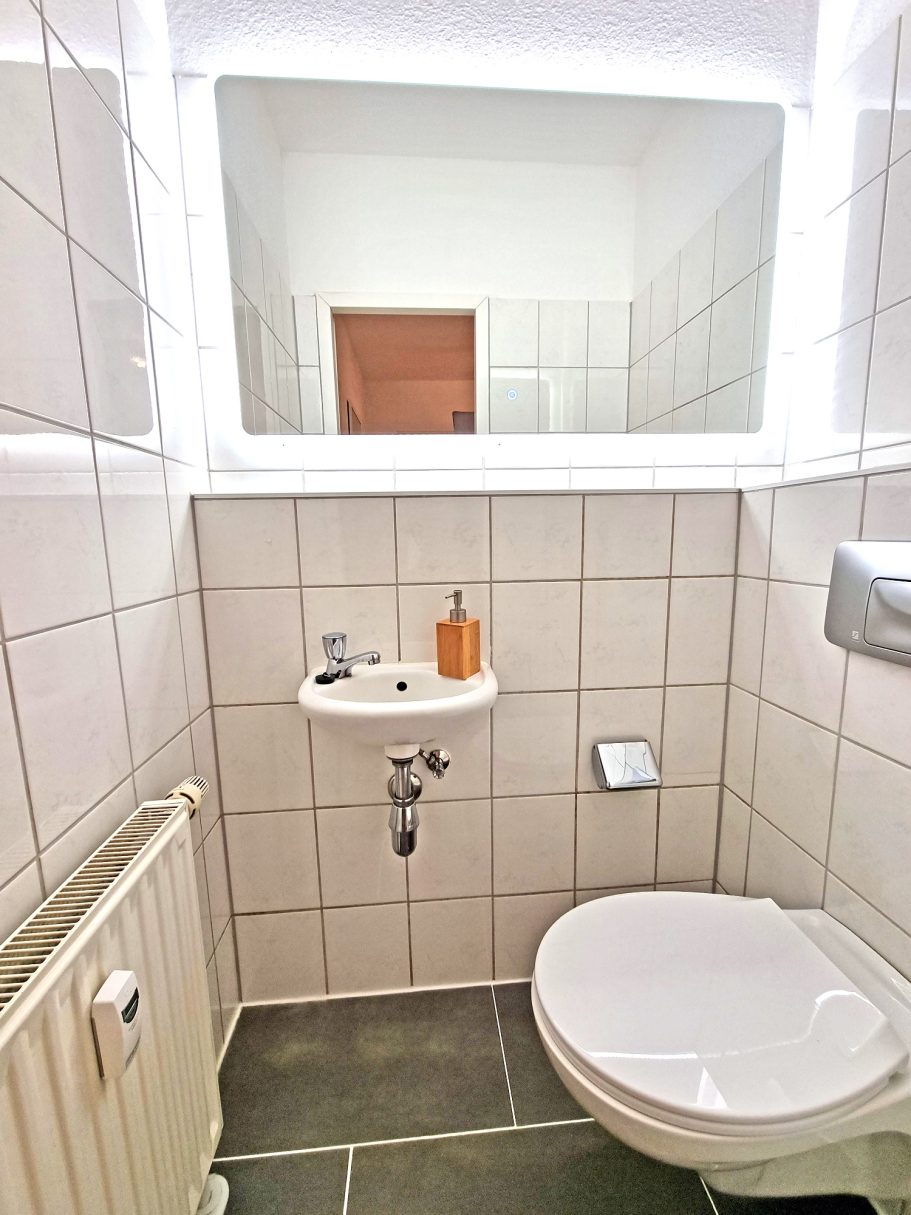 Kleines WC Kleines Badezimmer mit weißer Wandfliesen, Waschbecken und Toilette.